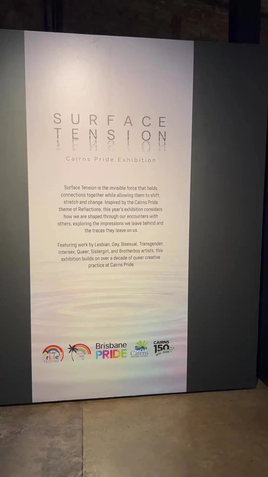 The Surface Tension title wall at the entry to Tank 4, its exhibition text printed over rippling water between two charcoal panels