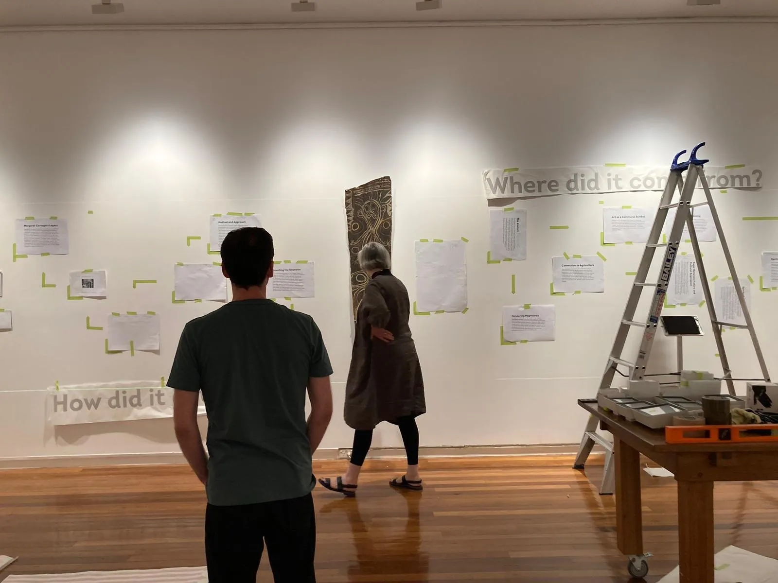 Two people look up at the finished wall while the question How did it get here is applied to the floor