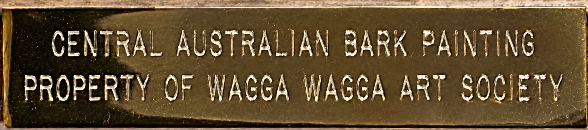A small engraved brass plate on the frame reading Central Australian Bark Painting, Property of Wagga Wagga Art Society