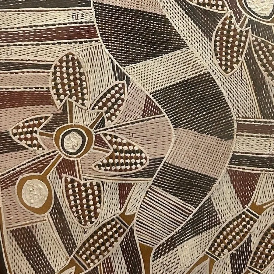A close-up of the lower part of the bark painting, with a flower-like form among bands of rarrk cross-hatching